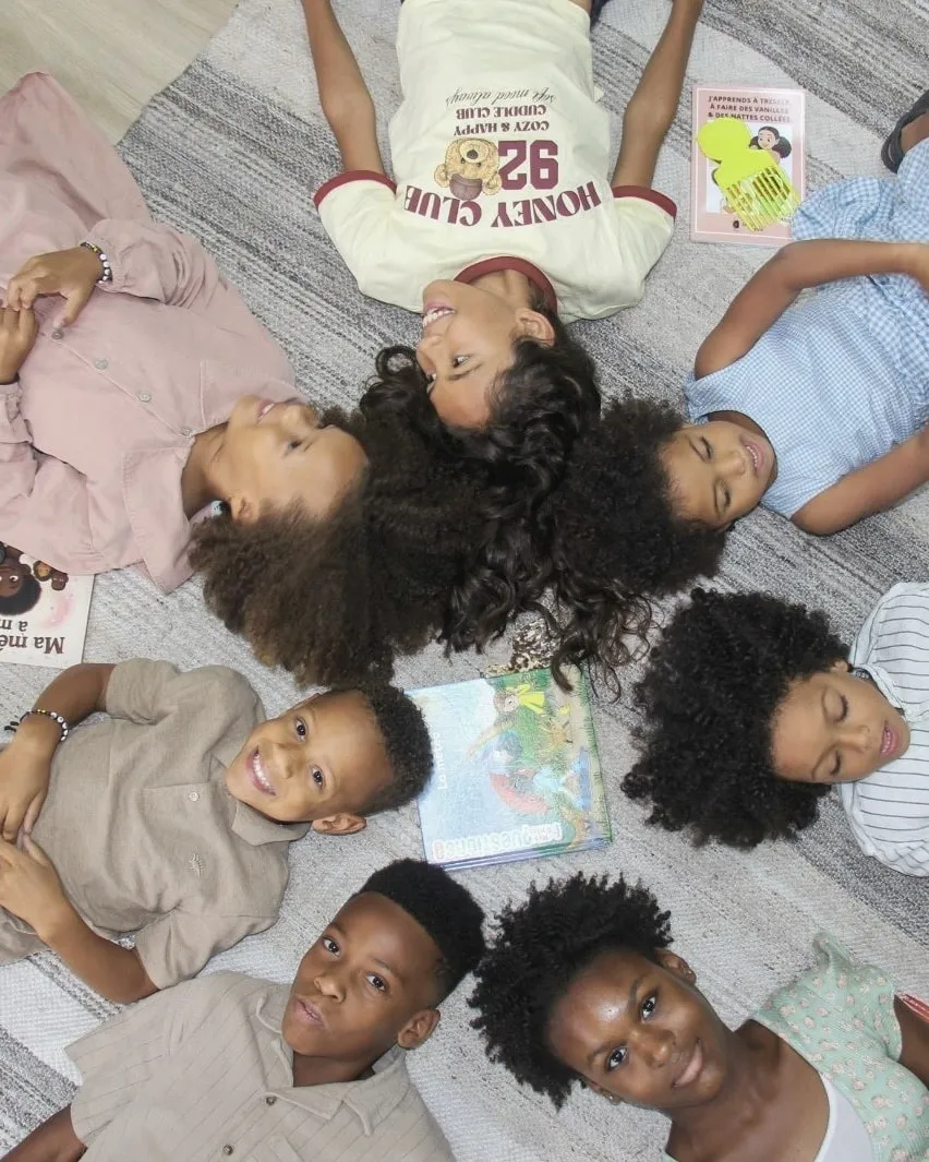 Coiffure enfant cheveux bouclés et crépus : enfants allongés en cercle autour de livres, Boucles Addict Studio Montréal