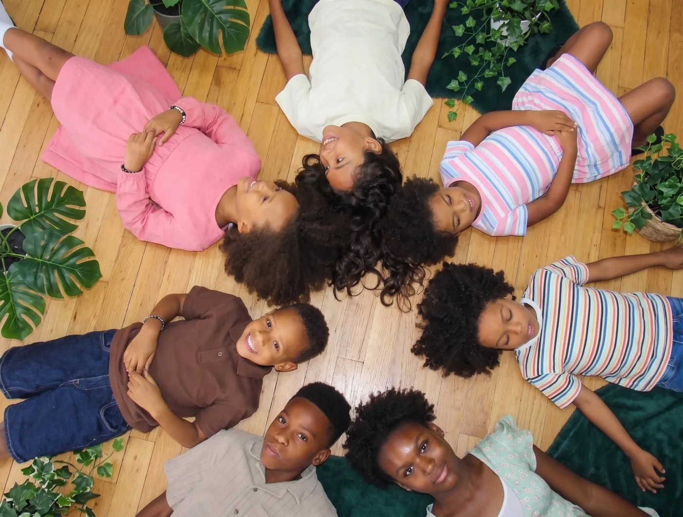 Seven kids with curly and coily hair lying in a circle
